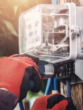 Electrician in red gloves wiring an electric meter on a utility pole