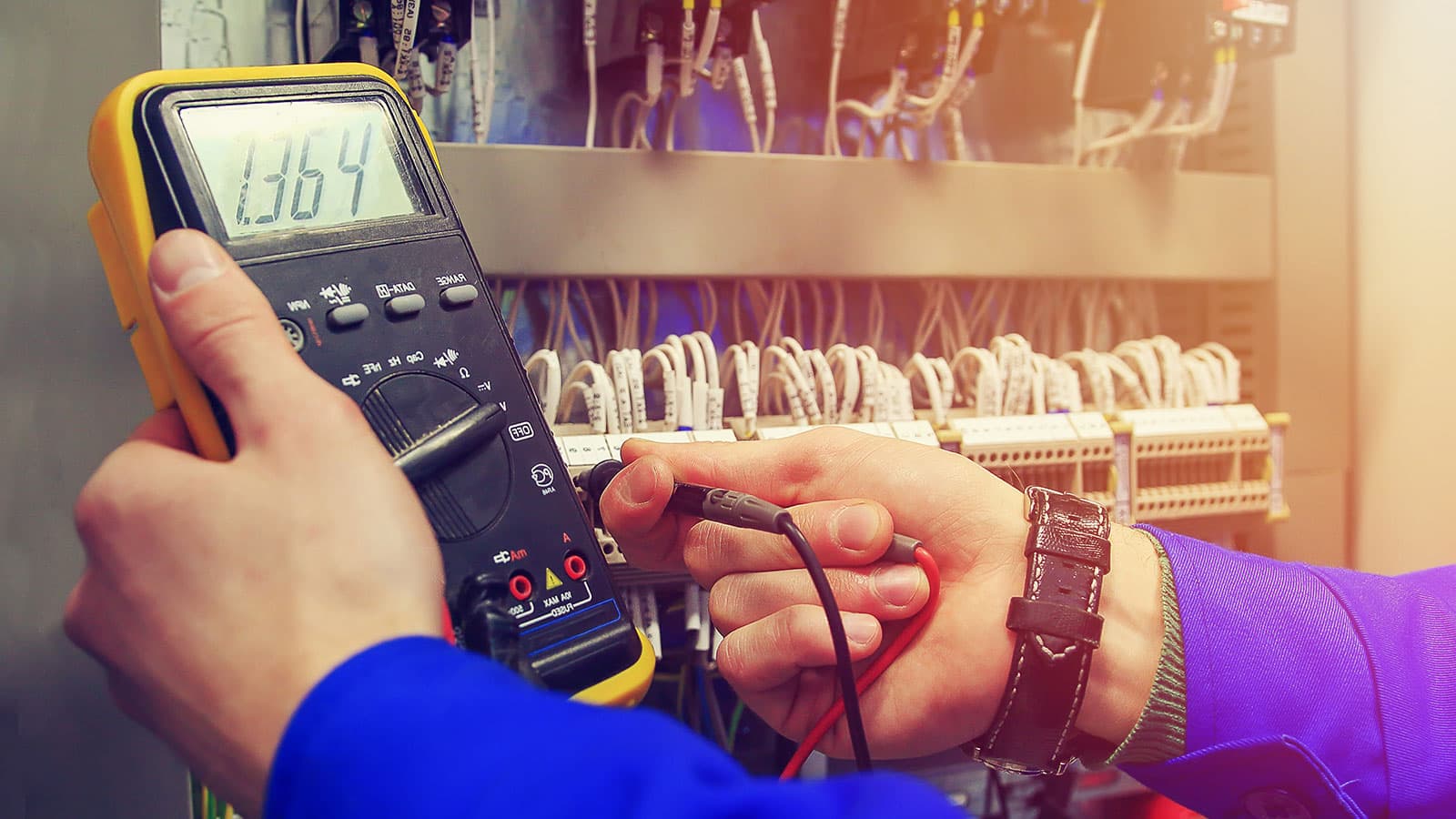 Electrician testing a control panel with a digital multimeter